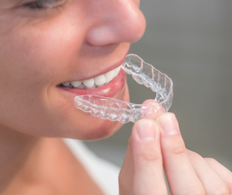 Patiente souriante tenant un aligneur dentaire transparent